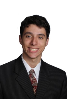 White male college student headshot. Brown hair and wearing a dark suit, whit shirt and muted color tie.