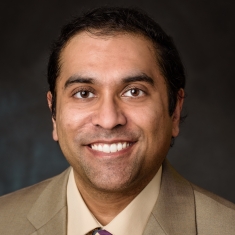 Head shot of Indian male with whort, dark brown hair, wearing a tan suit, with tan shirt, and tie.
