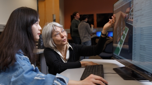 Female professor with students in front of desktop computer