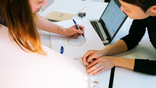 Two students at a workstation completing engineering homework