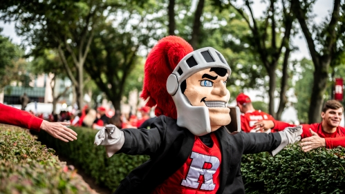 Scarlet knight costumed character outside with football fans