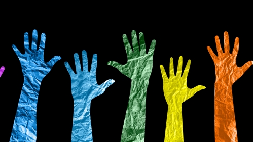 colorful cutout paper hands raised against a black background