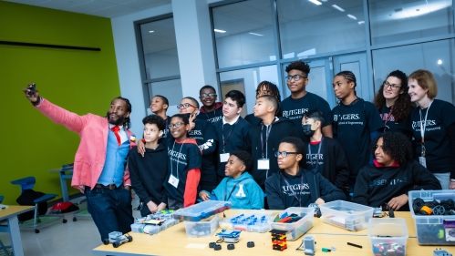 Large group of young black male students with their teachers taking a selfie.