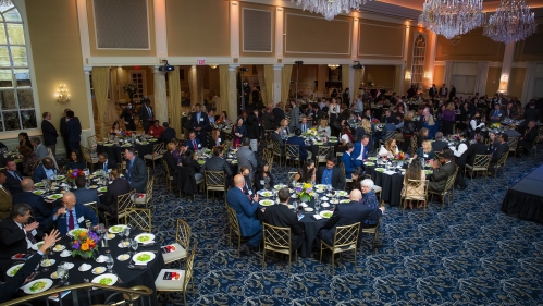 people seated around round tables preparing for dinner and award presentation ellence dinner