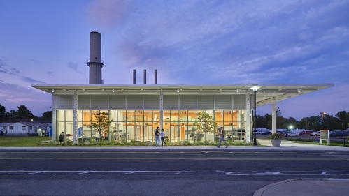 Photo taken at dusk of the Engineering Project Studio on the Rutgers Campus. The floor to ceiling glass walls are illuminated showing the inside of the building.