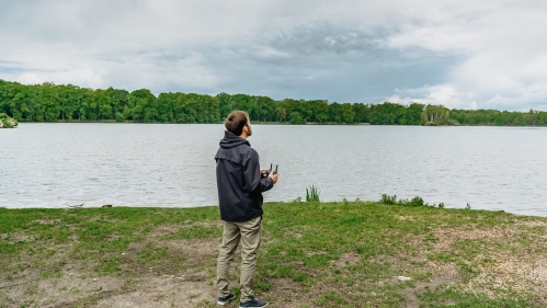 Male operating a drone on a river bank.