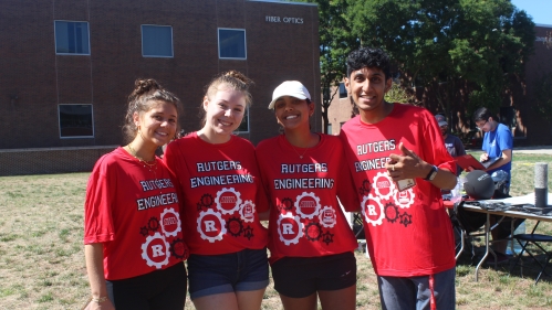 Four students standing outdoors wearing red Rutgers Engineering t-shirts.
