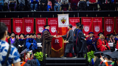 Students walk across stage to receive their diploma.
