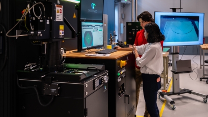 A male and female student working together on a machine with monitors