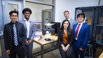 Group of five students, three male and one female, posing with their senior design drone project.