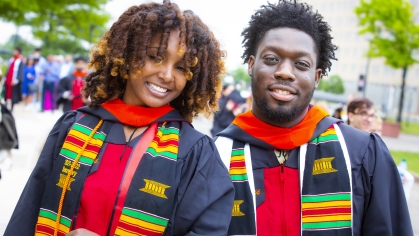 female and male student in regalia at graduation