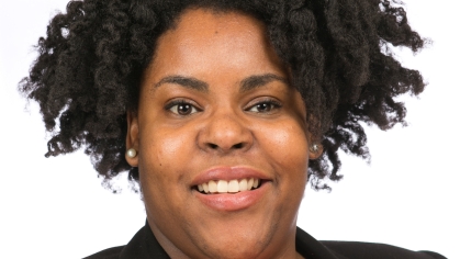 Head shot of African American woman with short black hair, wearing a black suit jacket with a red shirt.