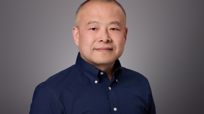 Headshot of male with very short hair wearing a blue button down shirt.