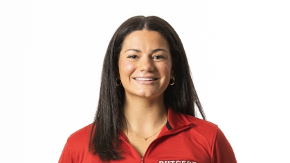 Female college student poses from the waist up with her hands behind her back. She has long black hair and is wearing red Rutgers pulloever.