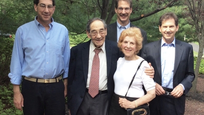Family photo of five adult sons posing outside around an elderly man and woman.