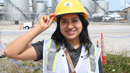 Female wearing a yellow hard hat and safety vest.