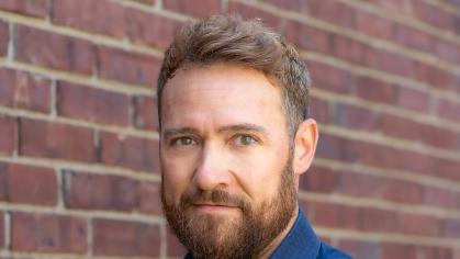Photo of man with arms crossed wearing a blue shirt