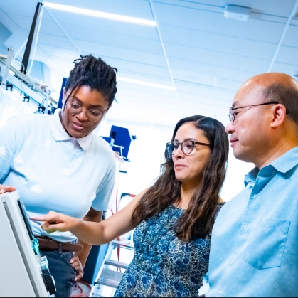 Two young woman along with a male professor working in a civil and environmental engineering water lab.