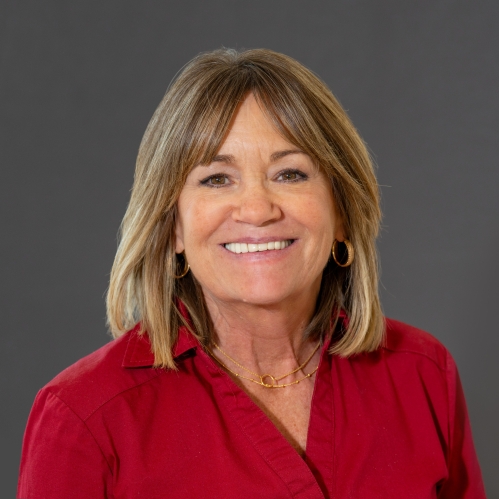 Head shot of woman with shoulder length brown hair, wearing a red collared shirt.