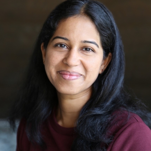 Headshot of smiling woman with long black hair wearing a burgundy top.