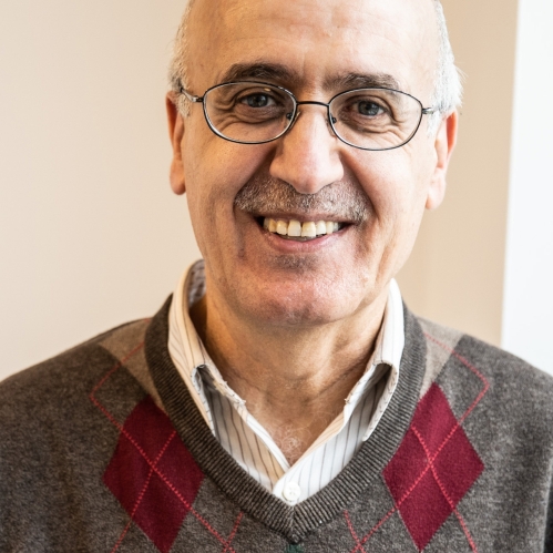Headshot of male with short white hair, wearing eyeglasses, and an argyle sweater.