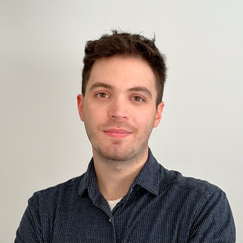 Headshot of male with short brown hair, wearing a dark blue patterned shirt.