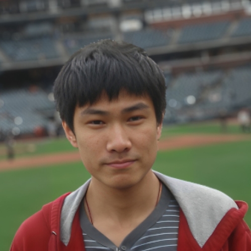 Headshot of male with black hair and bangs, wearing a grey striped shirt with a hooded grey and maroon sweatshirt.and