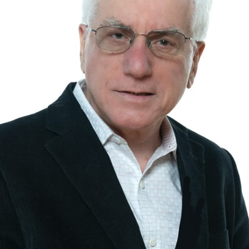 Male with shortwhite hair, and eyeglasses, wearing a black suit jacket and white button down shirt.