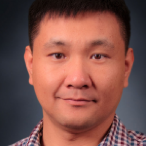 Headshot of male with black hair and blue, red, and white checkered shirt.