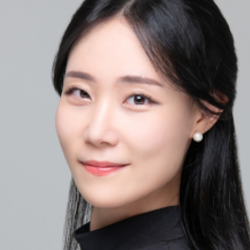 Headshot of Chinese woman with long black hair wearing pearl earrings and a black turtleneck.