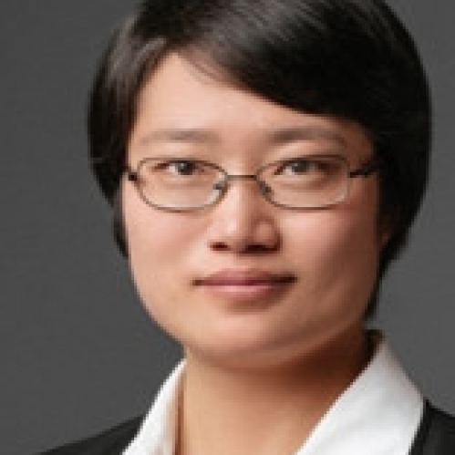 Headshot of woman with short black hair, wearing eyeglasses, a white button down shirt, and a black suit jacket.