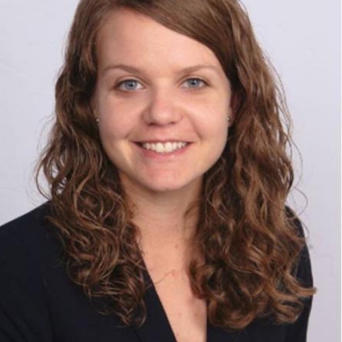 Headshot of female with long, wavy, light hair, wearing a black suit jacket.