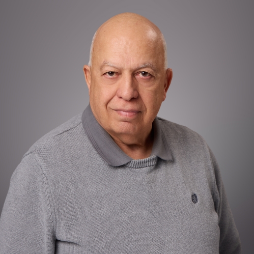 Headshot of bald male wearing a grey pullover sweater.