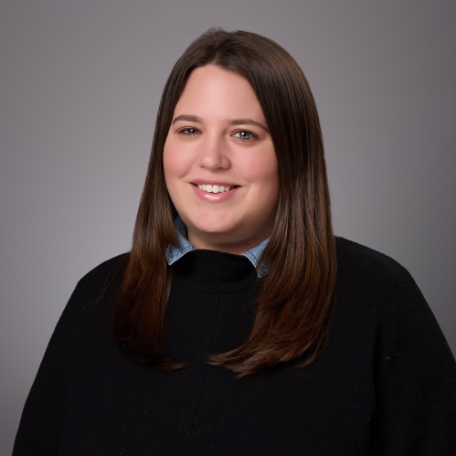Headshot of female with long dark brown hair, wearing a black pullover.