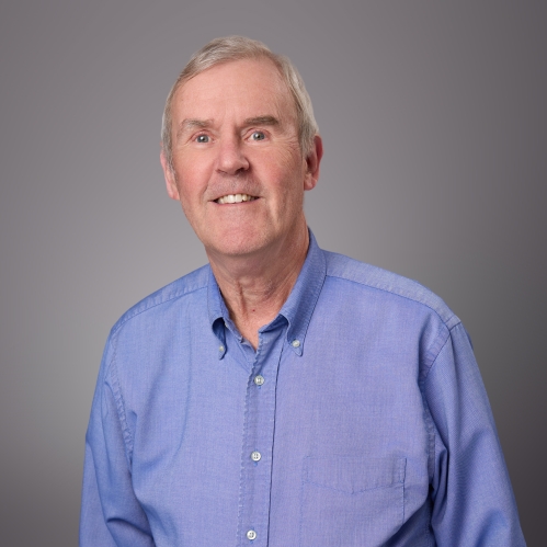 Headshot of male with short grey hair wearing a blue button down shirt.