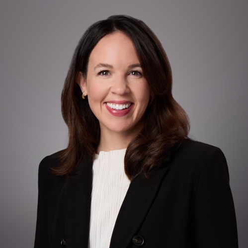 Headshot of wman with long brown hair wearing a beige blouse under a black suit jacket.