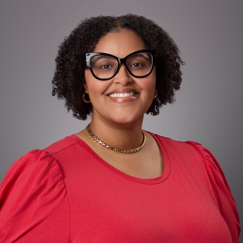 Headshot of black female with short curly hair and eyeglasses wearing a red blouse with a necklace.