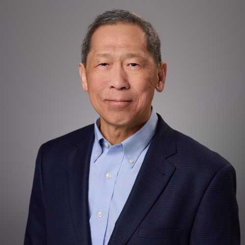 Headshot of male wearing a light blue button down shirt and a dark blue shit jacket.