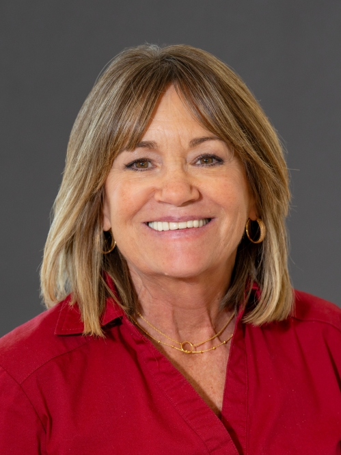Head shot of woman with shoulder length brown hair, wearing a red collared shirt.