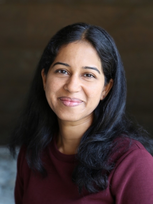 Headshot of smiling woman with long black hair wearing a burgundy top. 