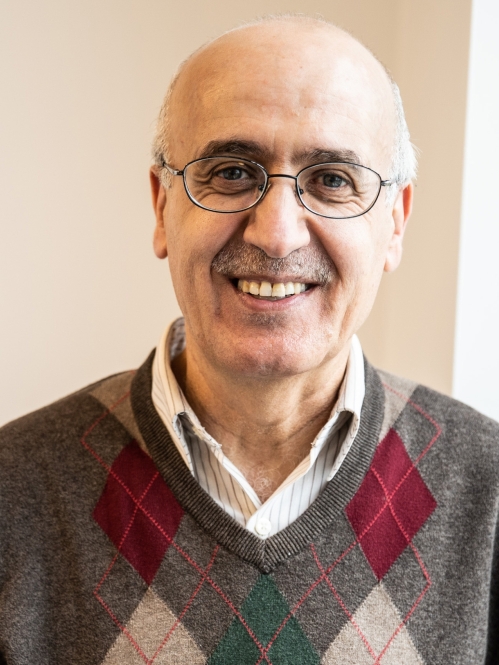 Headshot of male with short white hair, wearing eyeglasses, and an argyle sweater.