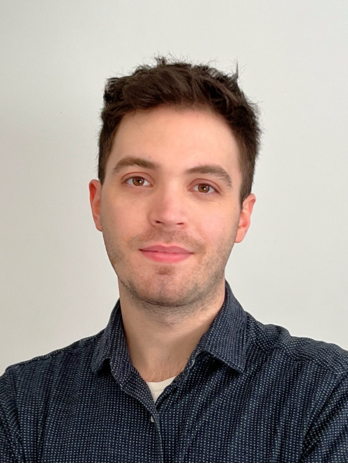 Headshot of male with short brown hair, wearing a dark blue patterned shirt.