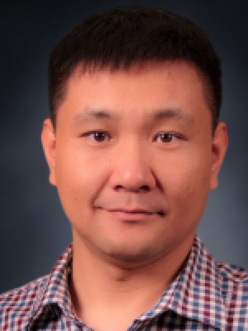 Headshot of male with black hair and blue, red, and white checkered shirt.