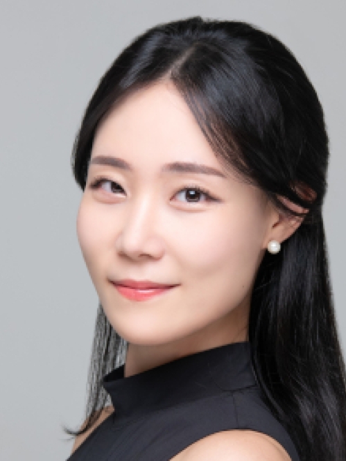 Headshot of Chinese woman with long black hair wearing pearl earrings and a black turtleneck.