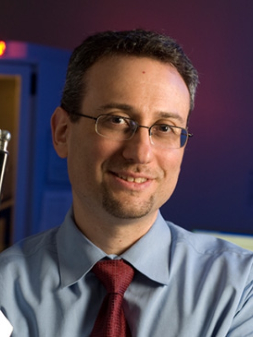 Headshot of male with eyeglasses, wearing a light blue shirt and burgundy tie.