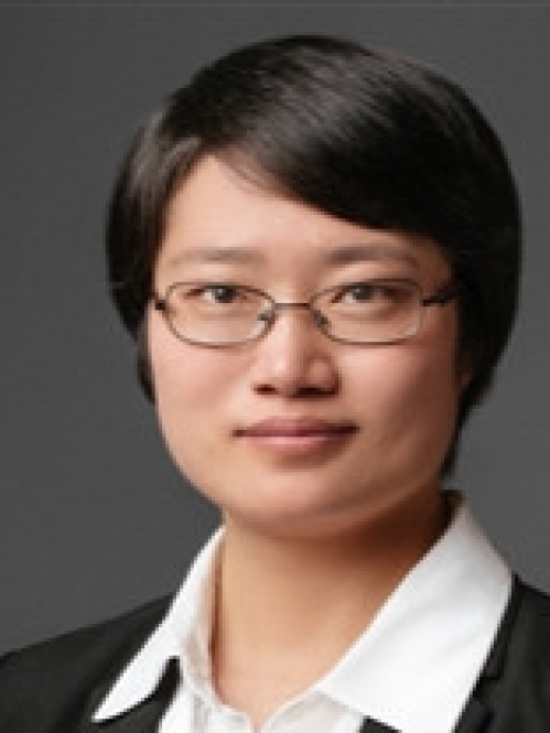 Headshot of woman with short black hair, wearing eyeglasses, a white button down shirt, and a black suit jacket.
