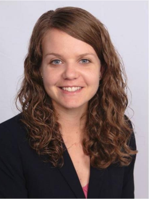 Headshot of female with long, wavy, light hair, wearing a black suit jacket.