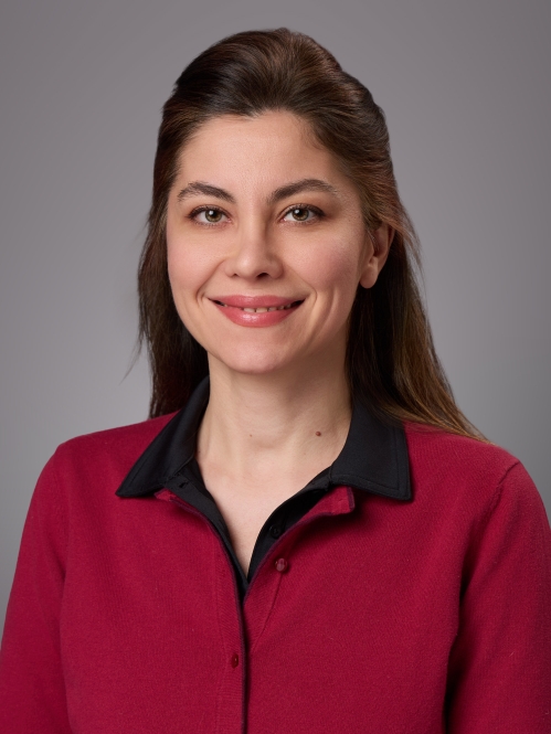 Headshot of woman with long brown hair wearing a red shirt with a black collar.