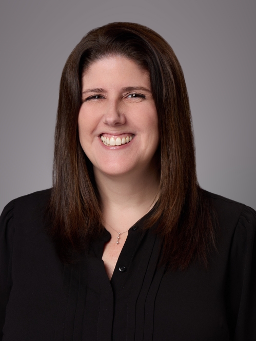 Headshot of woman with long brown hair wearing a black blouse.
