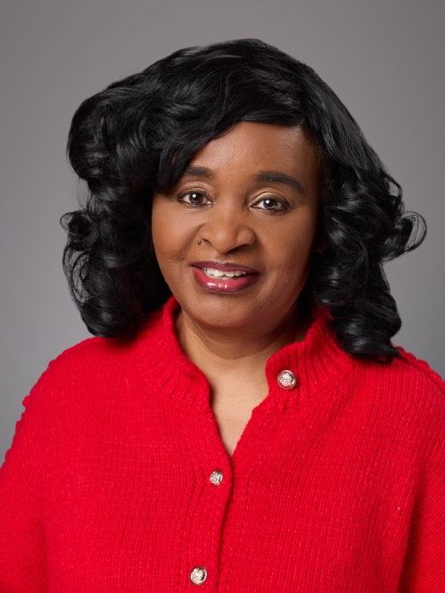 Headshot of black female with black shirt wavy hair wearing a red sweater.